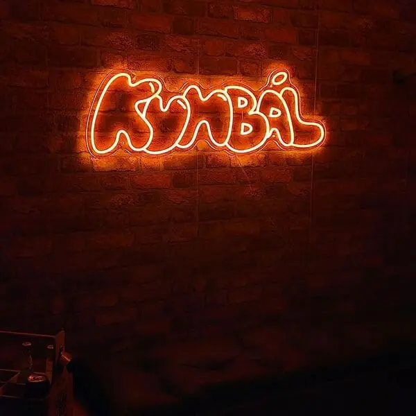 Oranžový neonový nápis Kumbál na cihlové stěně — realizace Neonworld